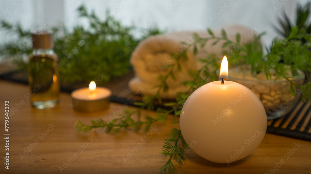 Background image of a lit candle in the foreground and spa decoration objects on the table