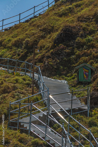 A staircase is shown on a hillside with a green shed in the background