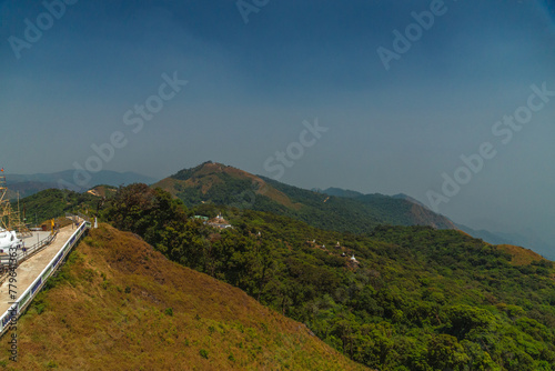 A mountain range with a forest on top and a road in the foreground