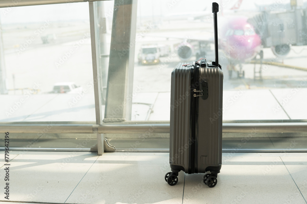 Suitcases in airport departure lounge and the airplane in background.Travel concept with hand luggage in the airport terminal waiting area, summer vacation concept. Suitcases in airport departure lounge and the airplane in background.Travel concept with hand luggage in the airport terminal waiting area, summer vacation concept.