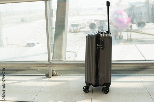 Suitcases in airport departure lounge and the airplane in background.Travel concept with hand luggage in the airport terminal waiting area, summer vacation concept.