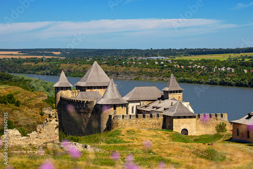 Blurred purple thistle flowers in the foreground and Khotyn fortress on background