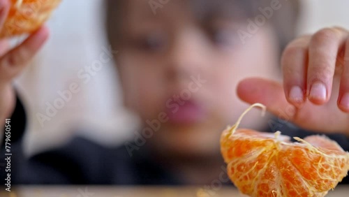 Child Sharing Food - Little Boy Splits Tangerine Into Two Halves And Then Offers One Half To His Companion photo