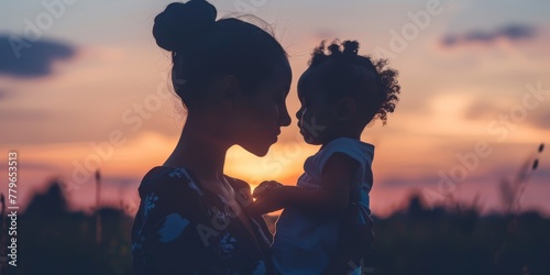 A woman and a child are holding hands in a field at sunset. Scene is warm and loving, as the mother and daughter share a special moment together