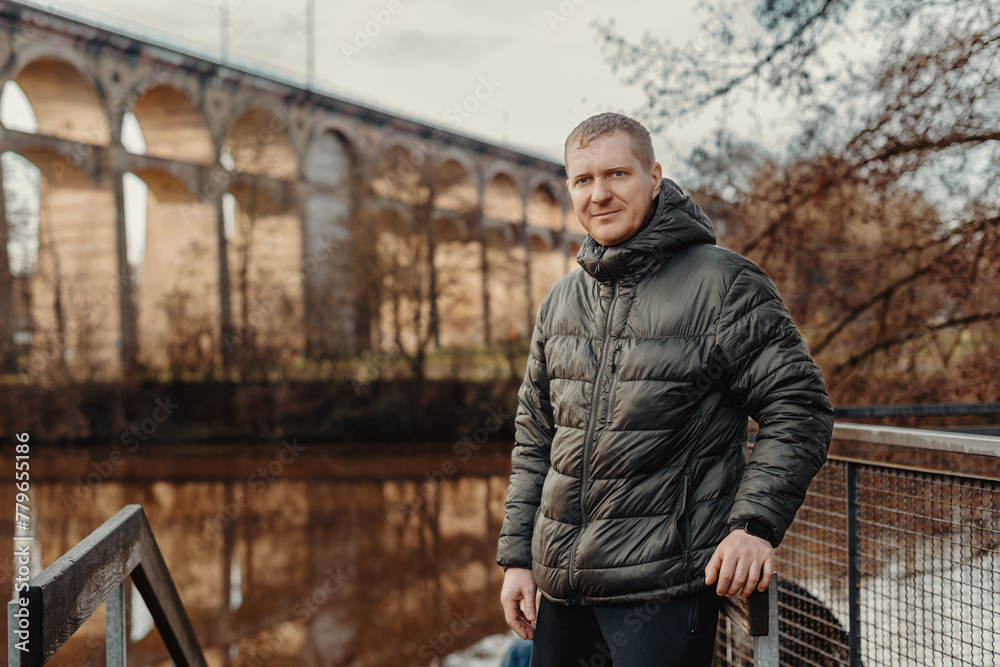 Timeless Elegance: 40-Year-Old Man in Stylish Jacket by Neckar River and Historic Bridge in Bietigheim-Bissingen, Germany