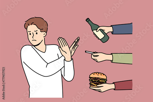 Man gives up bad habits, making forbidden gesture near hands with alcohol and cigarettes or fast food. Guy says stop bad habits to start healthy lifestyle and avoid loss of immunity