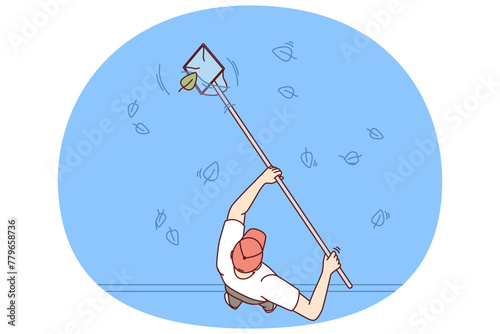 Man cleans pool or pond from leaves fallen from autumn trees to prevent rotting and water contamination. Guy using skimmer is standing near pool on territory of hotel, working in cleaning service