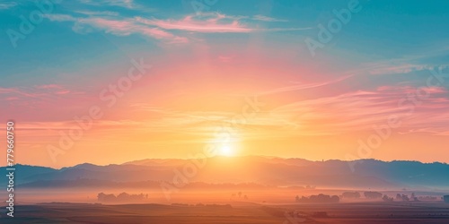 A beautiful sunrise over a mountain range with a bright orange sun in the sky. The sky is filled with clouds, creating a serene and peaceful atmosphere © kiimoshi