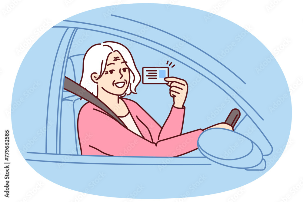 Naklejka premium Happy elderly woman demonstrates driver license sitting behind wheel of car and rejoices at opportunity to go on road trip. Positive grey-haired old lady got driver ID after retirement