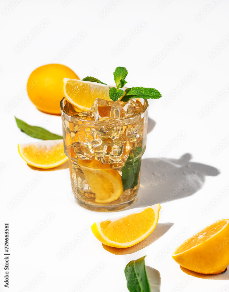 Fototapeta premium Iced tea with lemon and mint on white background with a shadow and citrus fruits.