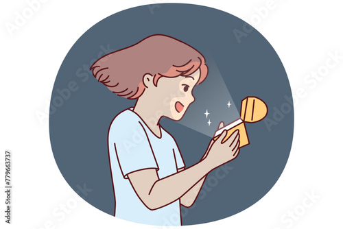 Little girl opens golden box and is delighted to see contents shining and illuminating child face. Teenage girl with gift box rejoices at adorable birthday present that evokes positive emotions