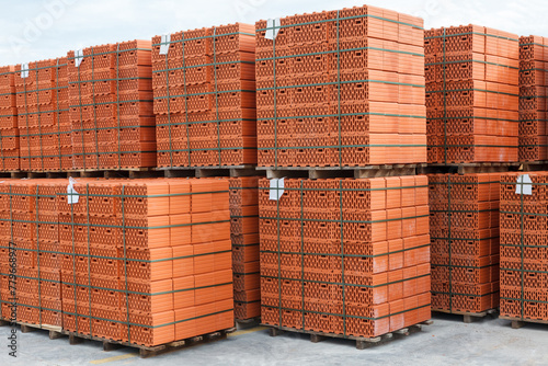 Stacks of new, red ceramic brick stacked on wooden pallets.