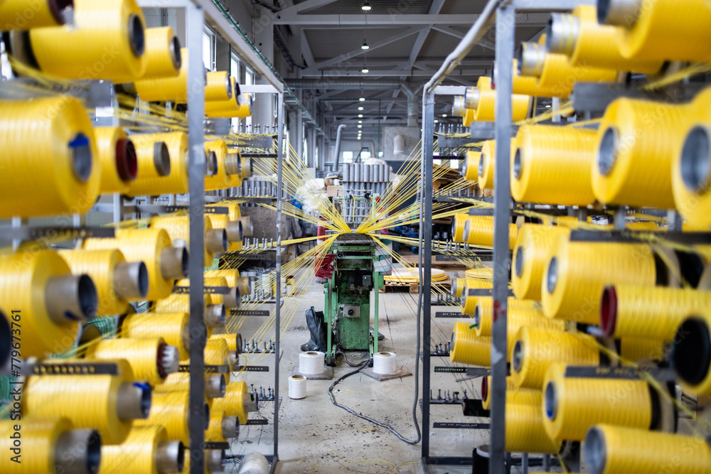 Industrial knitting machine with thread spool inside textile factory.