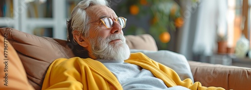 An optimistic and upbeat elderly man sitting on a sofa is seen from the side profile. photo