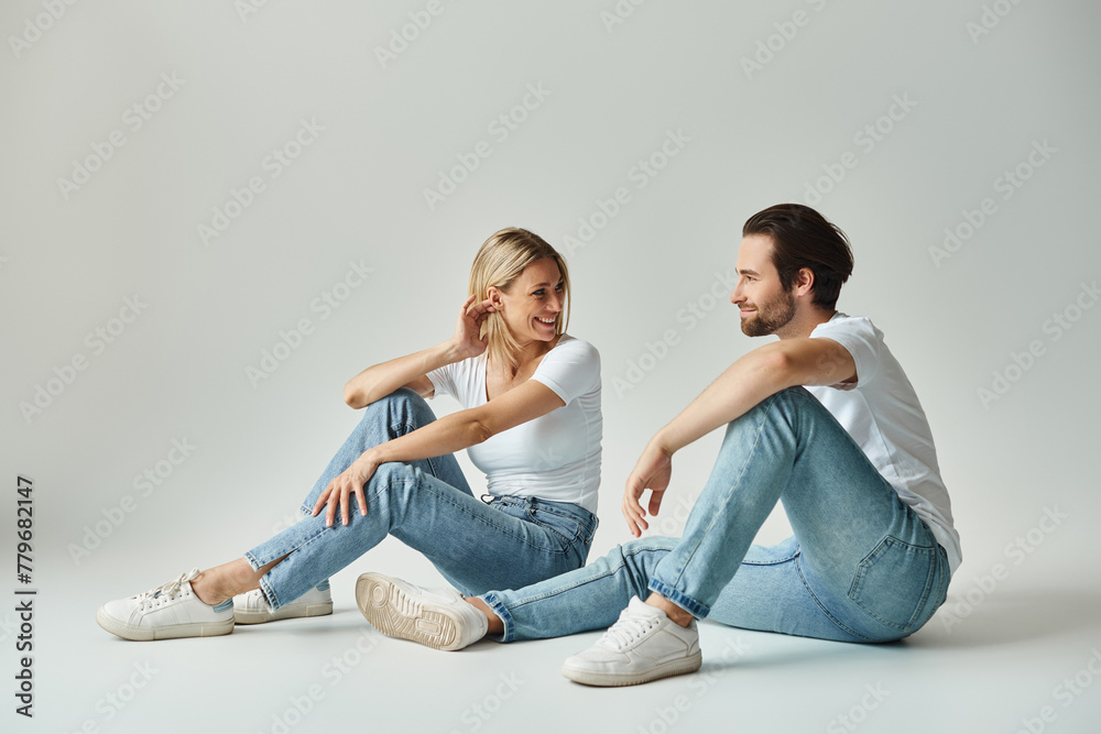 A man and a woman sit intimately on the ground, exuding serene vibes while engaged in a loving embrace. A man and a woman sit intimately on the ground, exuding serene vibes while engaged in a loving embrace.