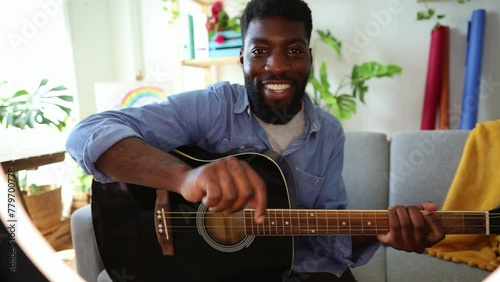 young African American musician records himself playing guitar while touching the screen to start filming