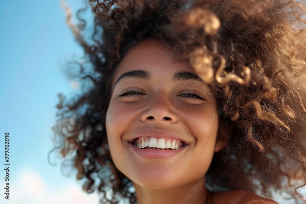 portrait of curly smiling woman with flying hair, sunny day, blue sky portrait of curly smiling woman with flying hair, sunny day, blue sky