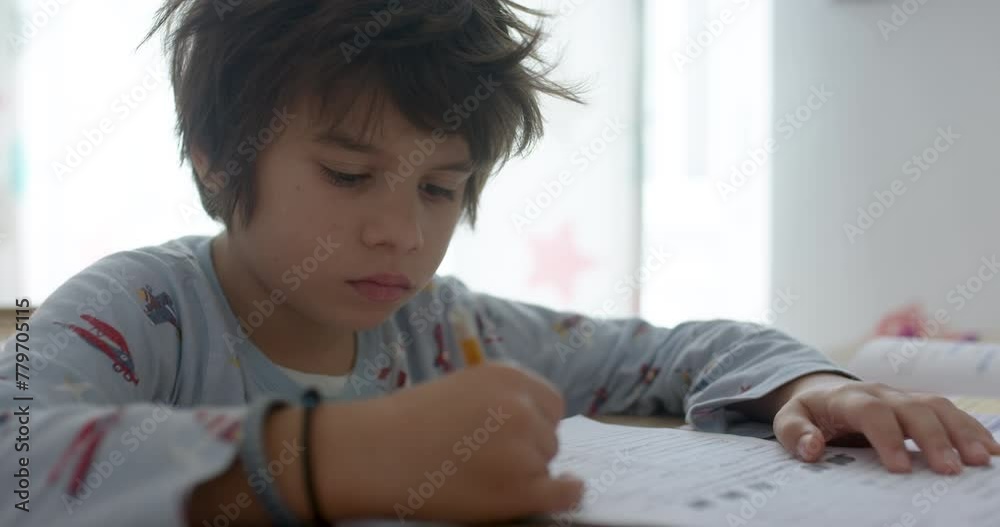 Young boy intently writing homework at a bright home desk during daytime Young boy intently writing homework at a bright home desk during daytime