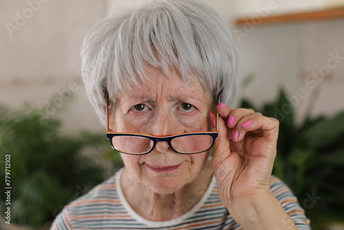 Senior woman squinting and putting her eyeglasses down 