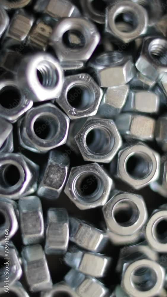 Many stainless hex nuts rotating close-up. Metal industry concept. Vertical video. Many stainless hex nuts rotating close-up. Metal industry concept. Vertical video.