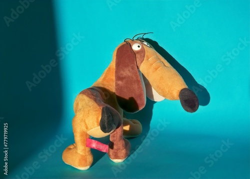close-up of a half-turn soft toy of a funny light brown dachshund on a blue background with a shadow on the wall