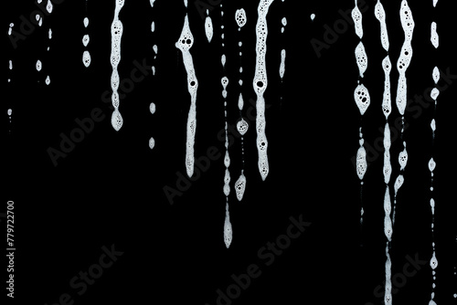 soap foam dripping from window glass, white foam on black background