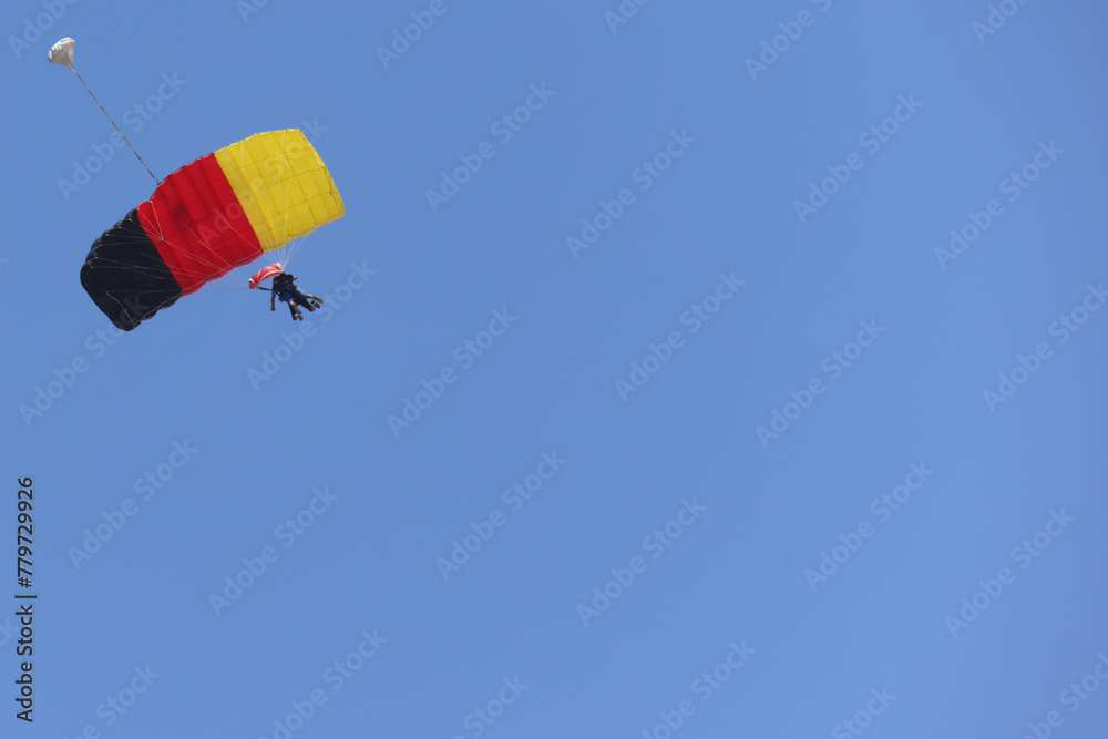 Tandem skydiving (parachuting), clear blue sky day. Parachute decorated in the Germany flag colors. Copy space. Tandem skydiving (parachuting), clear blue sky day. Parachute decorated in the Germany flag colors. Copy space.