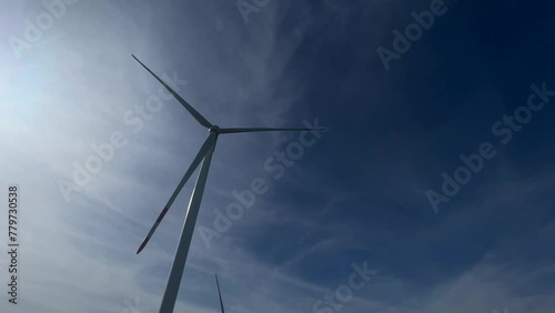 Wind turbine produce energy, modern power plant, alternative energy sources. Wind turbine rotating with blue sky on background.