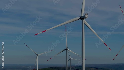 Wind turbines farm on blue sky background. Ecologic energy generators. Green power generation concept.
