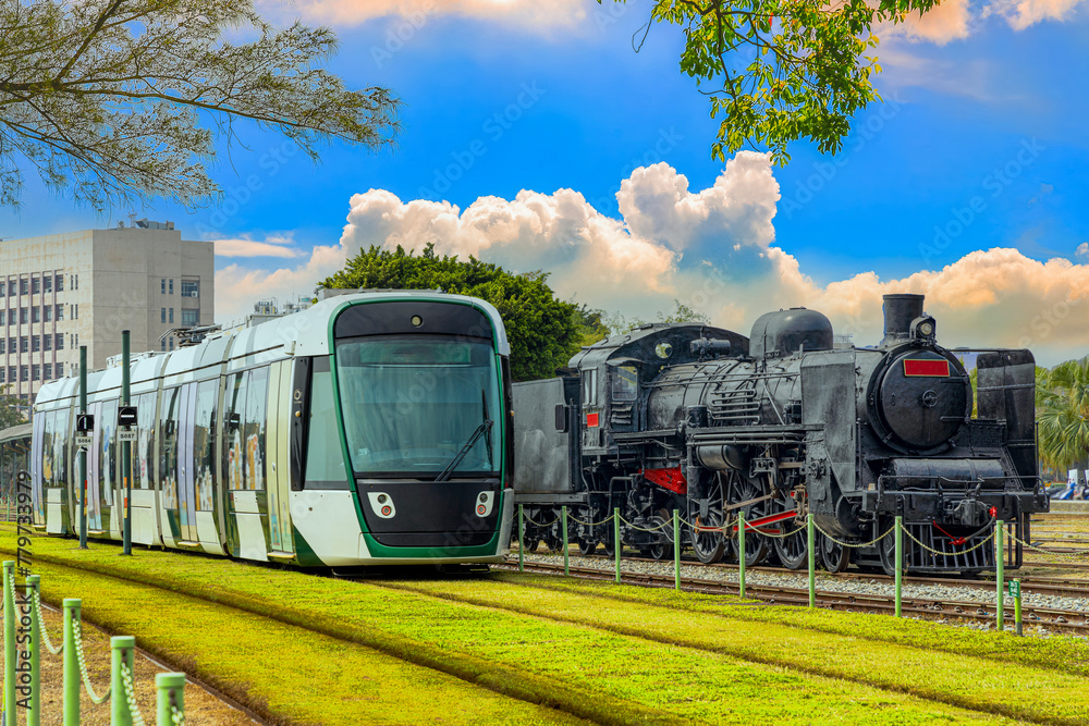 The electric light rail overtaking the steam locomotive symbolizes the evolution of the times and the progress of science. Hamasen Railway Cultural Park,Kaohsiung City,Taiwan.For branding, screensave.
