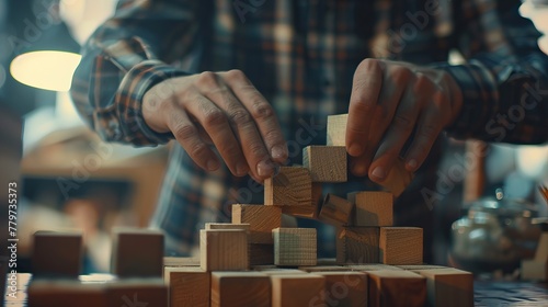 A business man attempts to build a structure with wooden blocks on a table, set against a blurred background, symbolizing business organization and startup concepts photo