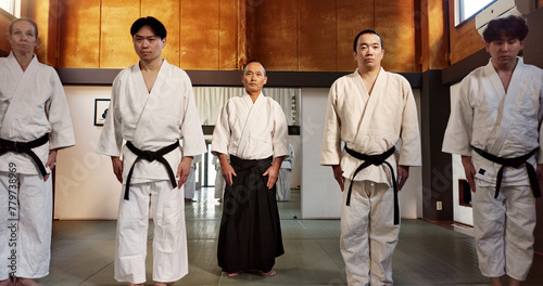 Japanese students, bow or learning aikido in dojo, training and modern martial arts for self defence or respect. Group, black belt class and sensei in instruction, honor and discipline in commitment