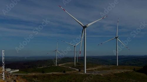 Wind power plants in the mountains. Powerful wind turbines, generating clean renewable green energy. Ecologic energy generators on beautiful sunny mountain landsape. Green power generation concept.