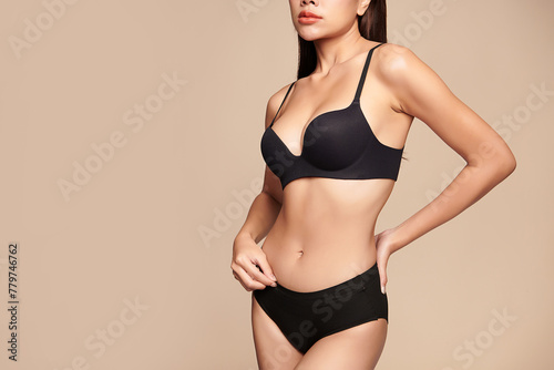 Confident beautiful young asian woman posing in black lingerie on beige background  Perfect body 