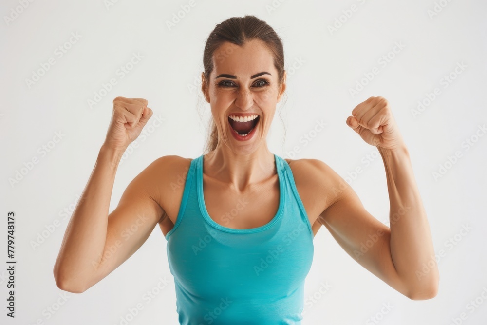 Energetic young woman triumphantly raising fists in a blue tank top Energetic young woman triumphantly raising fists in a blue tank top