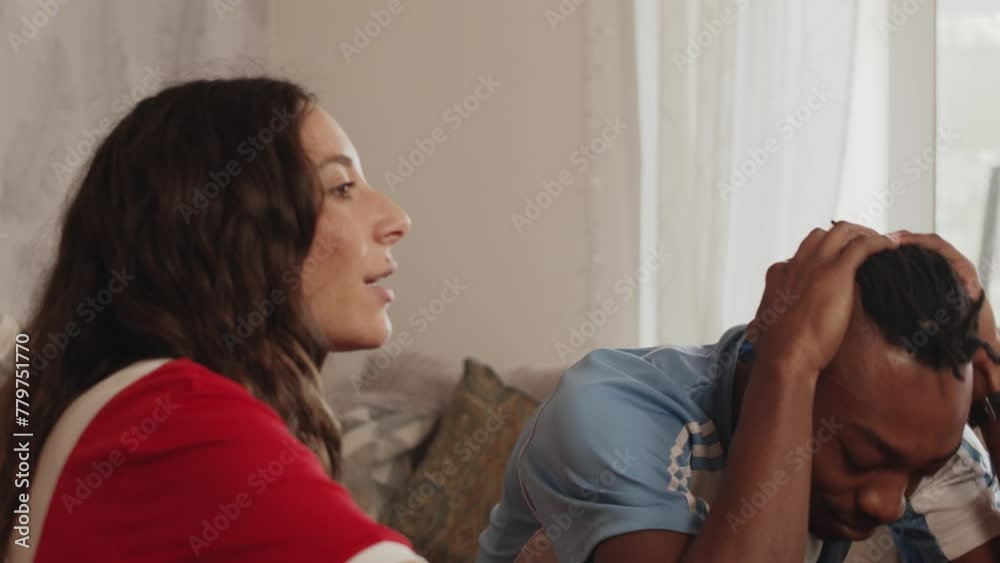 Rival football fans watch together at home blue team acts disappointed slow motion Rival football fans watch together at home blue team acts disappointed slow motion