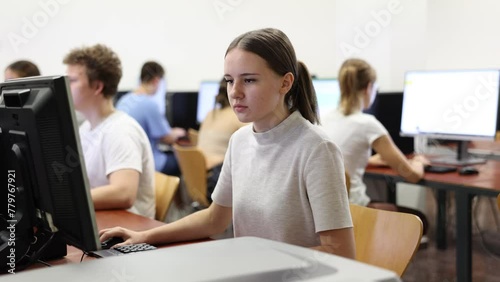 Smart female teenager learning computer science while she is using a PC in the computer classroom