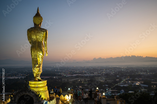 BiG golden buddha statue at Wat Phra That Khao Noi and Beautiful golden morning light, surrounding panorama of Nan city from the viewpoint area, Nan province, Thailand.