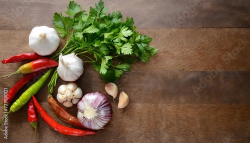 Overhead view of a wooden table with garlic, parsley and chilli. Copy space to the right.