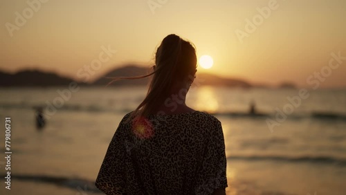 Young woman enjoying the sunset at sea. Close up happy long-haired girl relaxing on nature sea ocean landscape on seacoast at sunset, back view. Travel, enjoy life, adventure trip, freedom concept.