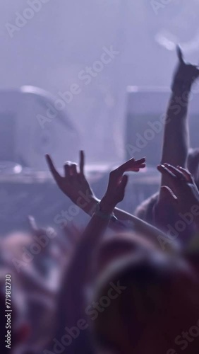 Fans at rock concert. People raising and claping their hands in stage lights. Unrecognizable fans dancing at a concert or festival party. Silhouettes of concert crowd , Vertical Screen