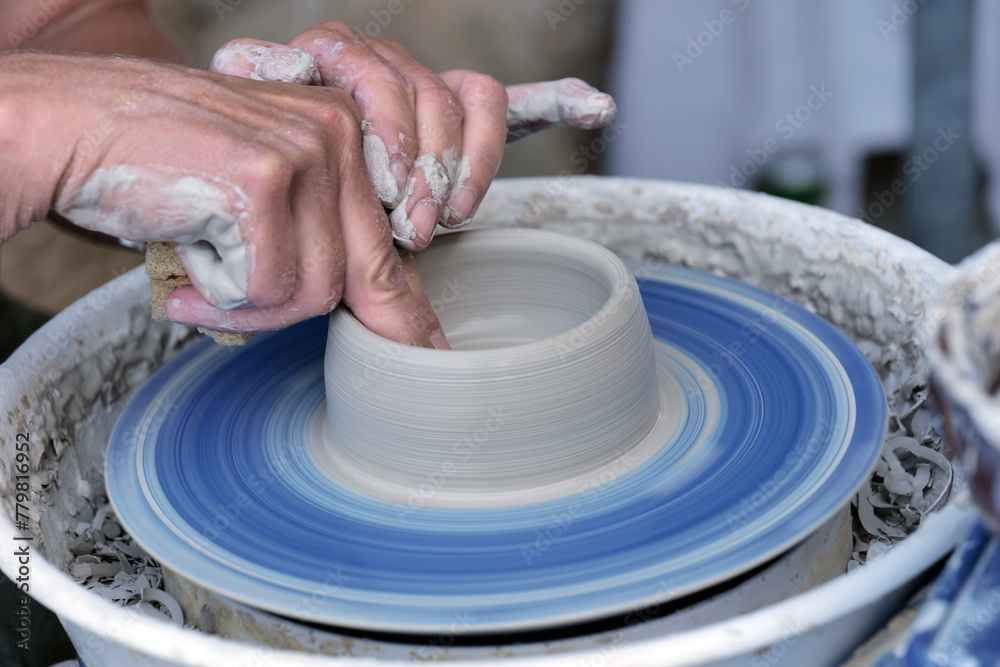 Female potter, ceramist working on pottery wheel while sitting in her workshop Female potter, ceramist working on pottery wheel while sitting in her workshop