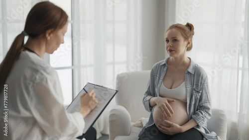 Pregnant woman consulting with a doctor. Smiling pregnant lady patient answers gynecologist questions at hospital, home, medical clinic. Doctor examine pregnant belly check up. Gynecology concept. photo