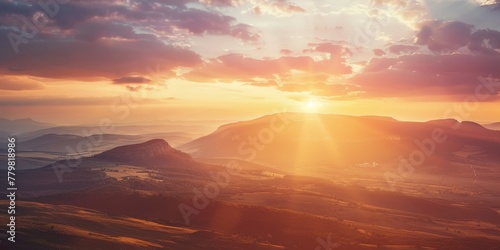 The sun is setting over a mountain range, casting a warm glow over the landscape. The sky is filled with clouds, creating a serene and peaceful atmosphere