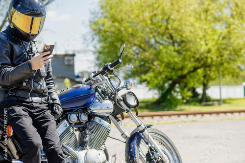 male motorcyclist with a smartphone near a classic custom chopper motorcycle