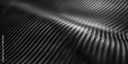 A close up of a black fabric with a shiny, reflective surface. The fabric appears to be made of carbon fiber, and it has a sleek, modern look to it. Concept of sophistication and elegance