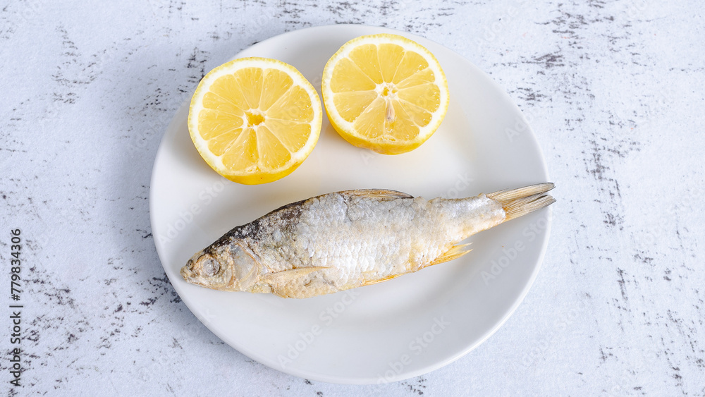 Smoked dried fish on plate with sliced lemons Smoked dried fish on plate with sliced lemons