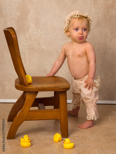 Blonde baby first steps holding chair
