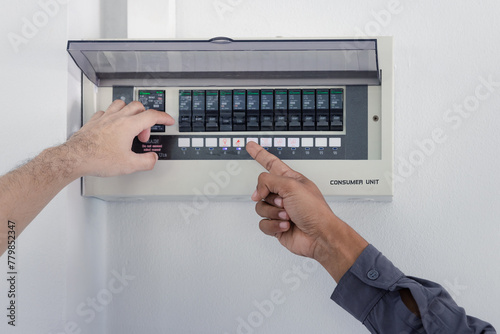 Resetting tripped breaker in residential electricity power control panel in homes and buildings. Men electrician turning off power for electrical outlet at circuit breaker box.