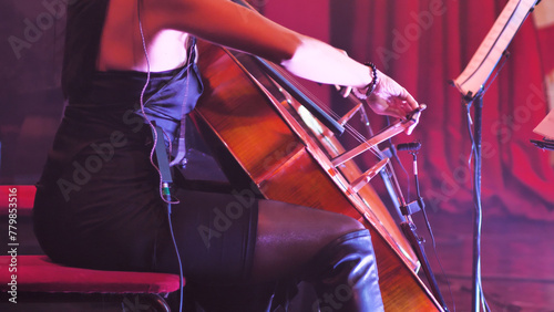 A talented woman passionately playing the cello onstage during a live performance, surrounded by stage lights. Her dedication and skill are evident in this captivating moment of musical harmony.